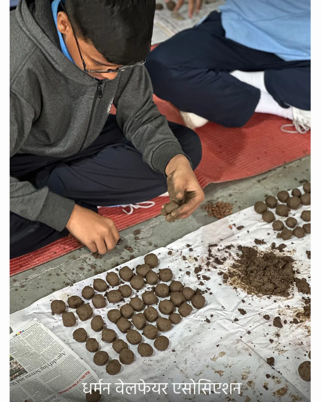 A student pressing seeds into a ball of soil.