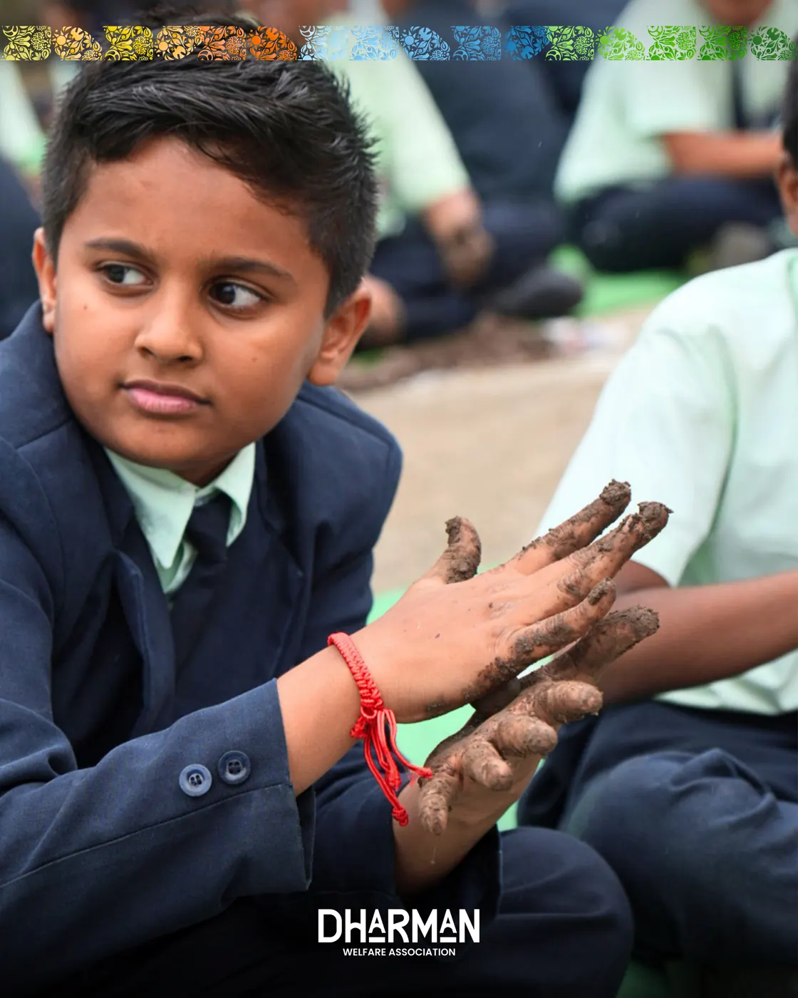 A student proudly holding up muddy hands after making seed balls.